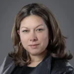 portrait photo woman with medium length brown hair wearing a black leather blazer