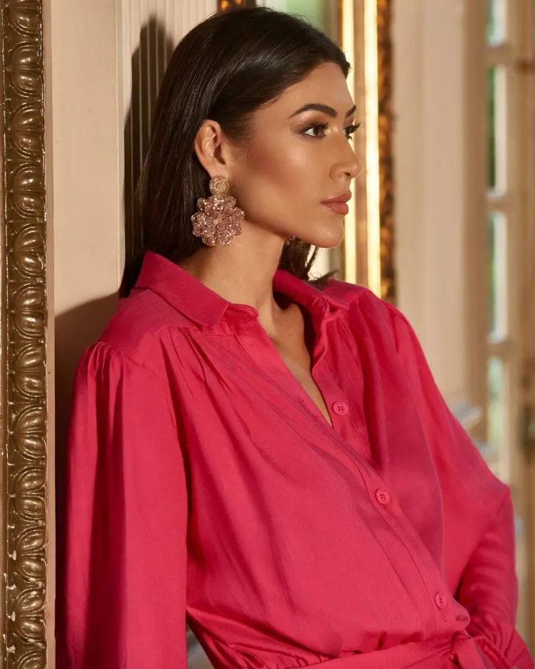 Woman with dark brown hair in red dress wearing a big gold flower shapped earring