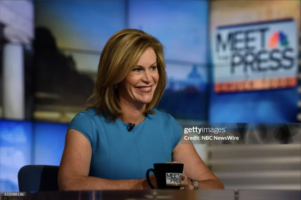 brunette woman on cast of meet the press sitting behind a desk smiling