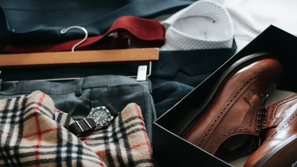 Top view photo of men's suit outfit and brown shoes laid out on a bed